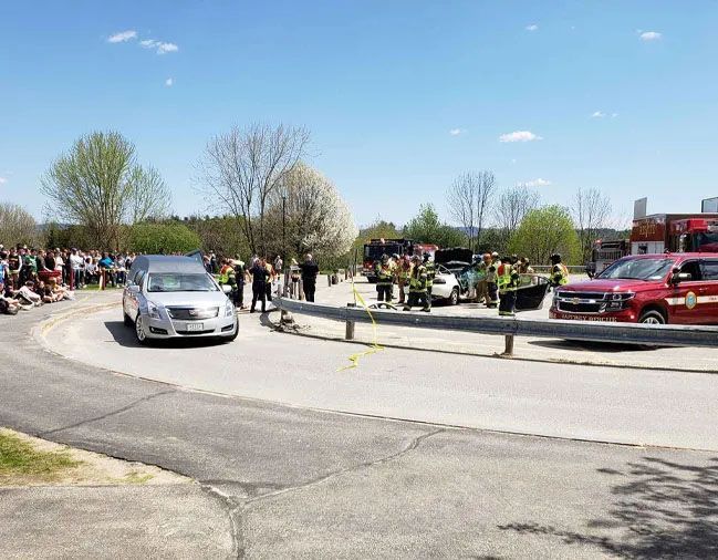 A car is driving down a road next to a group of people.