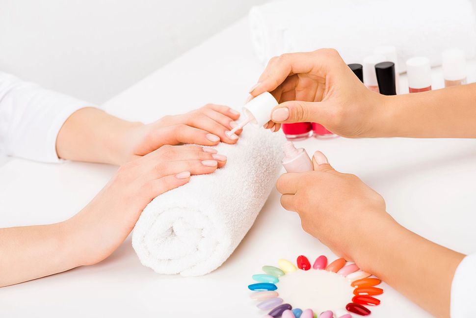 Hands receiving a manicure with nail polish in a bright salon setting