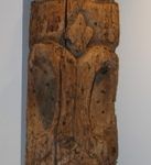 A wooden sculpture is hanging on a white wall.