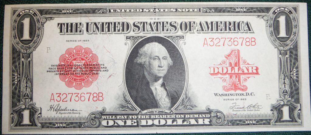 A green and white one dollar bill on a green surface.