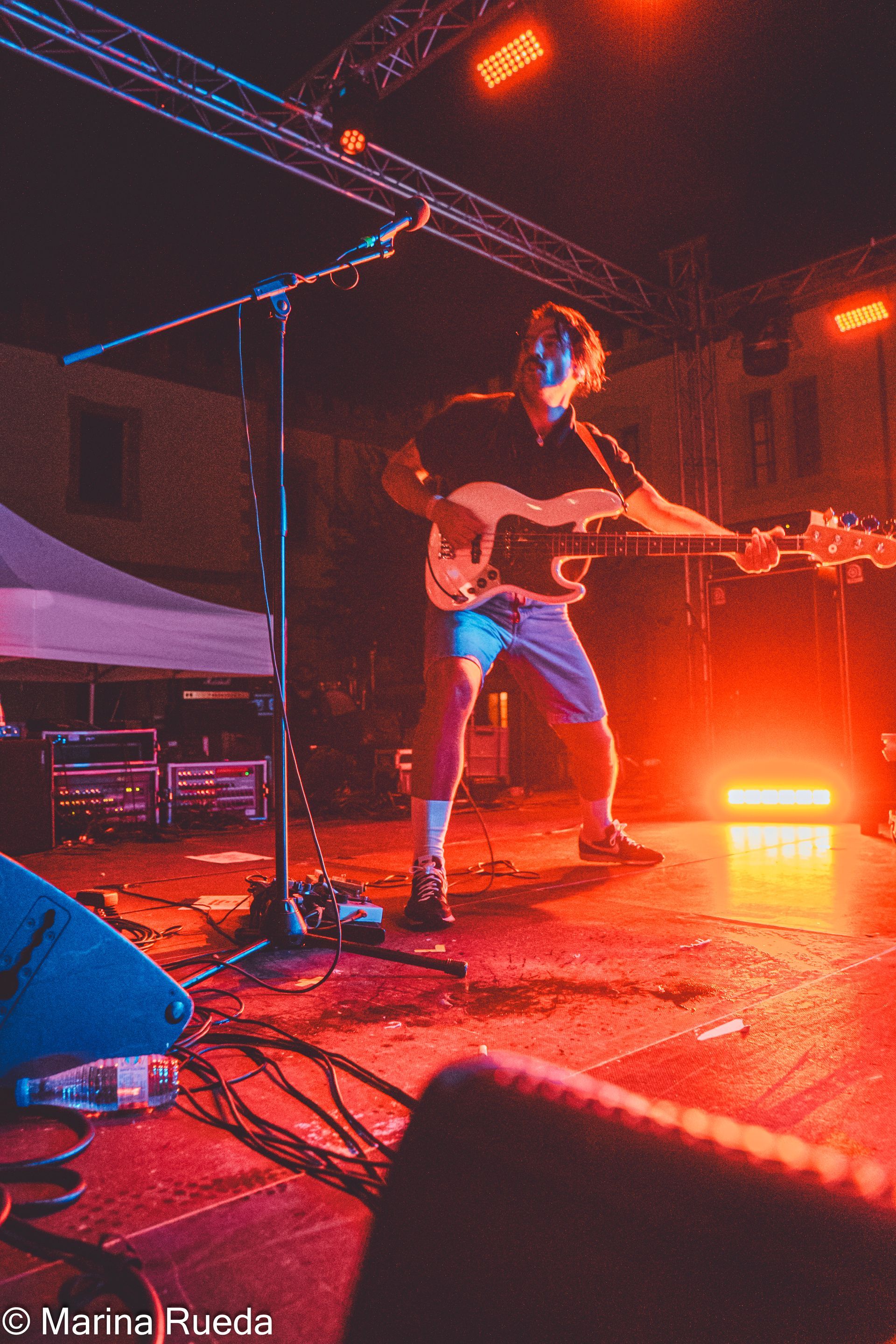 Un hombre está tocando una guitarra en un escenario por la noche.