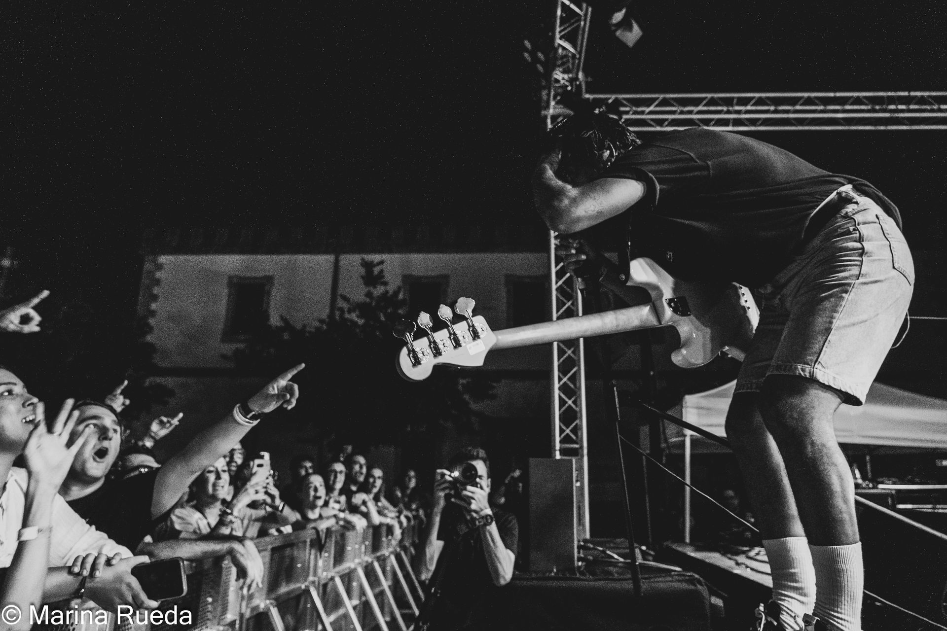 Una fotografía en blanco y negro de un hombre tocando una guitarra frente a una multitud.