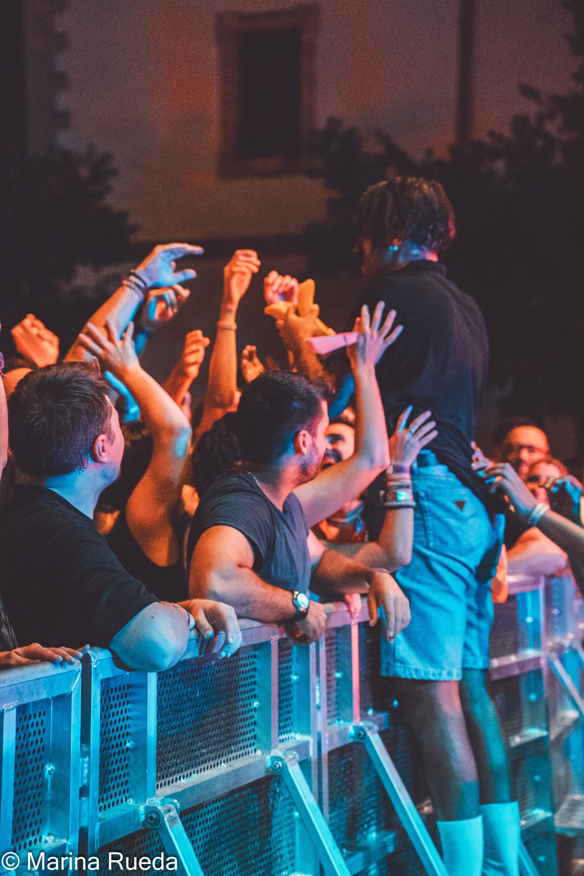 Un hombre está parado frente a una multitud de personas en un concierto.