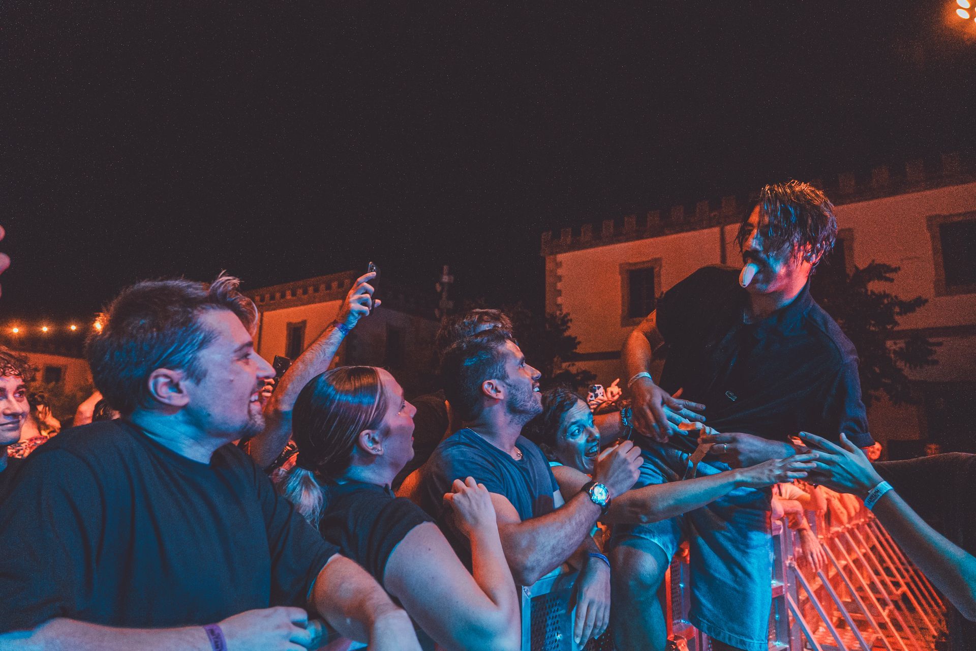 Un grupo de personas está de pie frente a un escenario en un concierto.