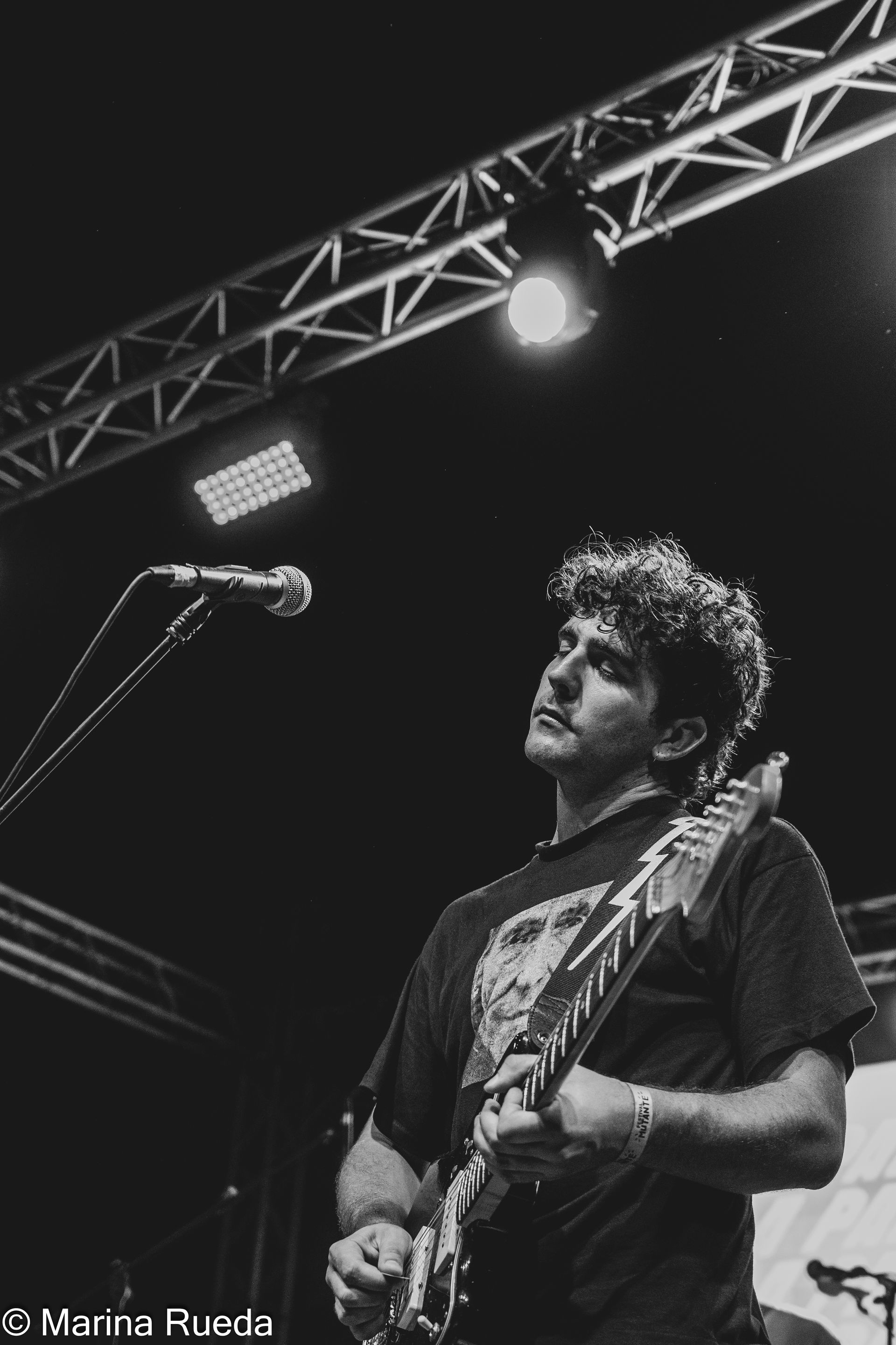 Un hombre toca una guitarra y canta con un micrófono en un escenario.