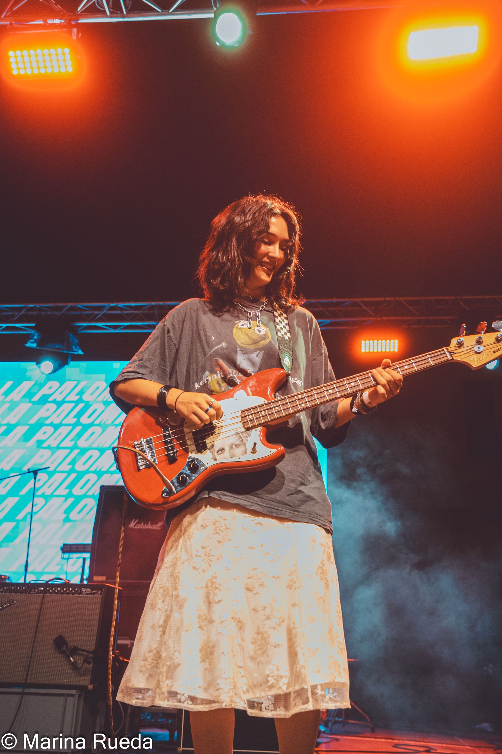 Una mujer está tocando una guitarra en un escenario.