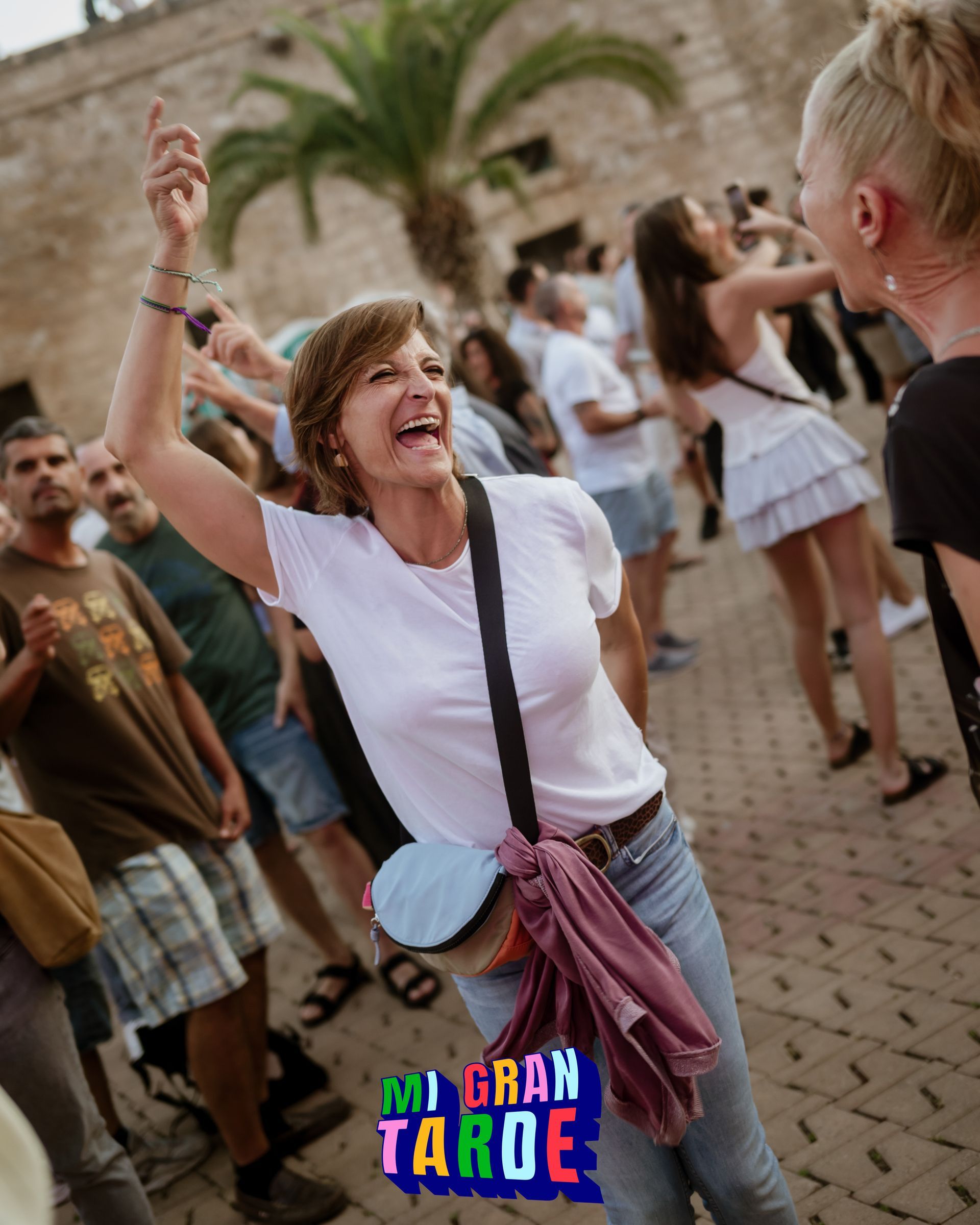Una mujer con una camisa blanca está de pie entre una multitud con un cartel que dice gran taroe