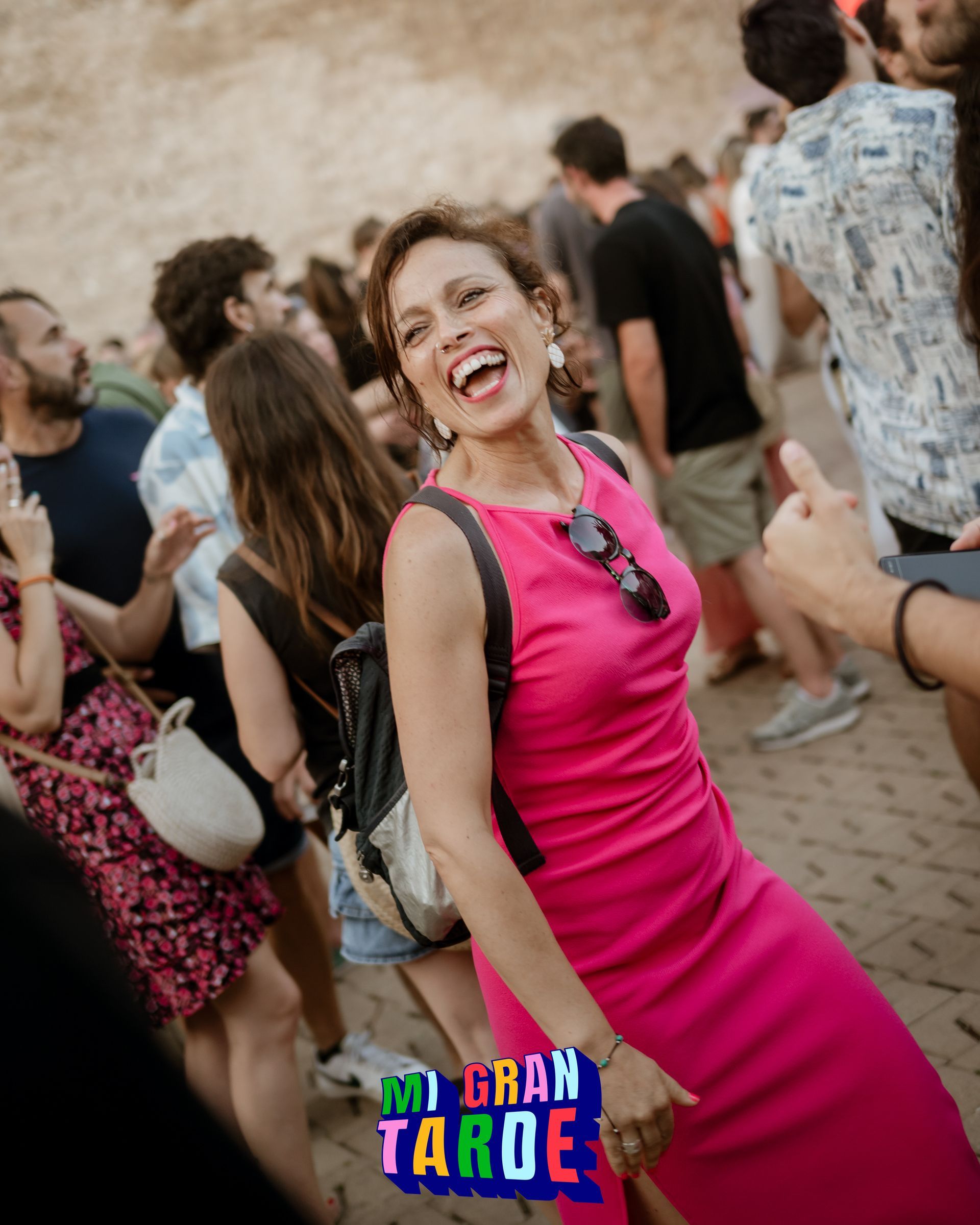 Una mujer con un vestido rosa está bailando entre la multitud.