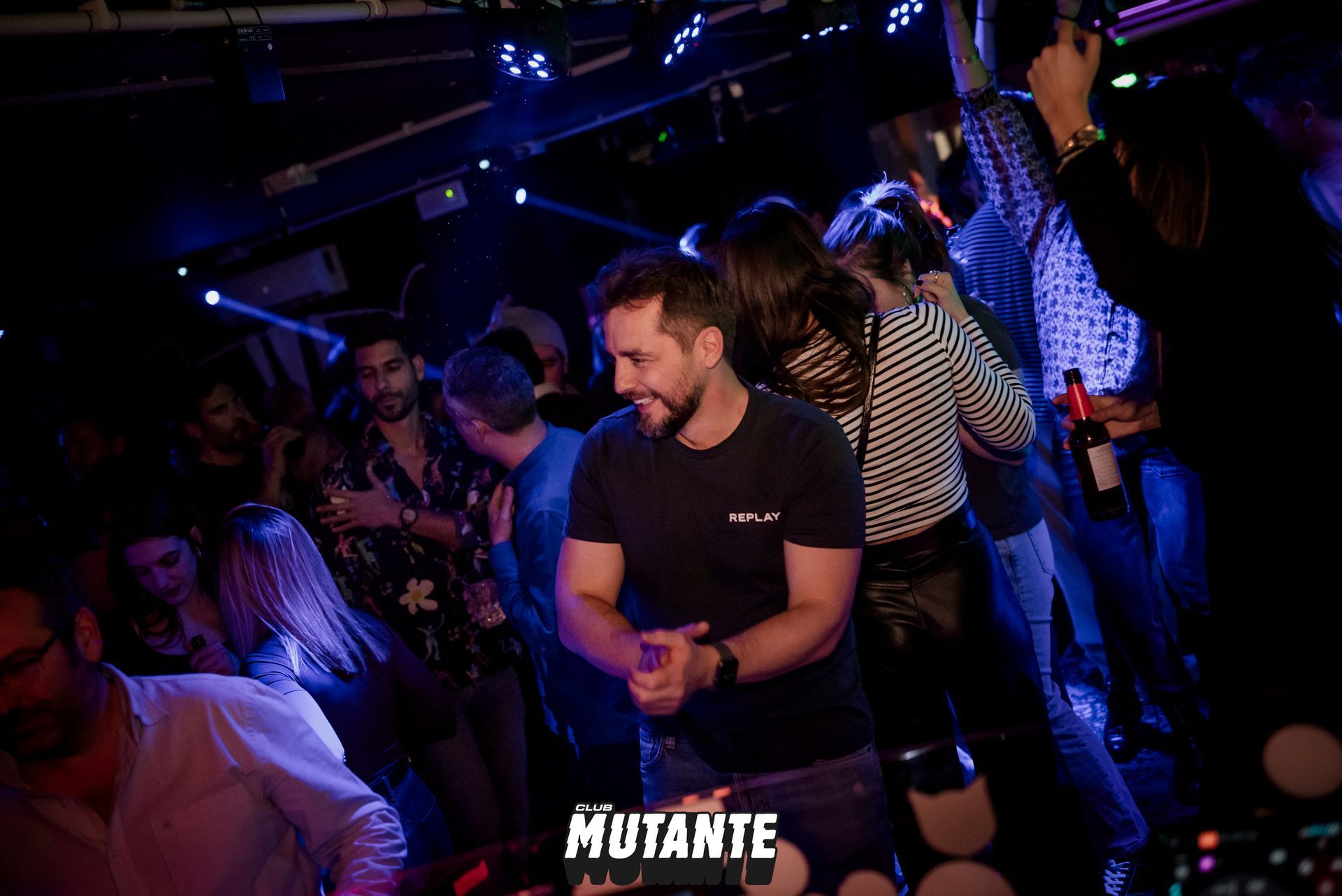 Un hombre está parado en medio de una multitud de personas en una fiesta.