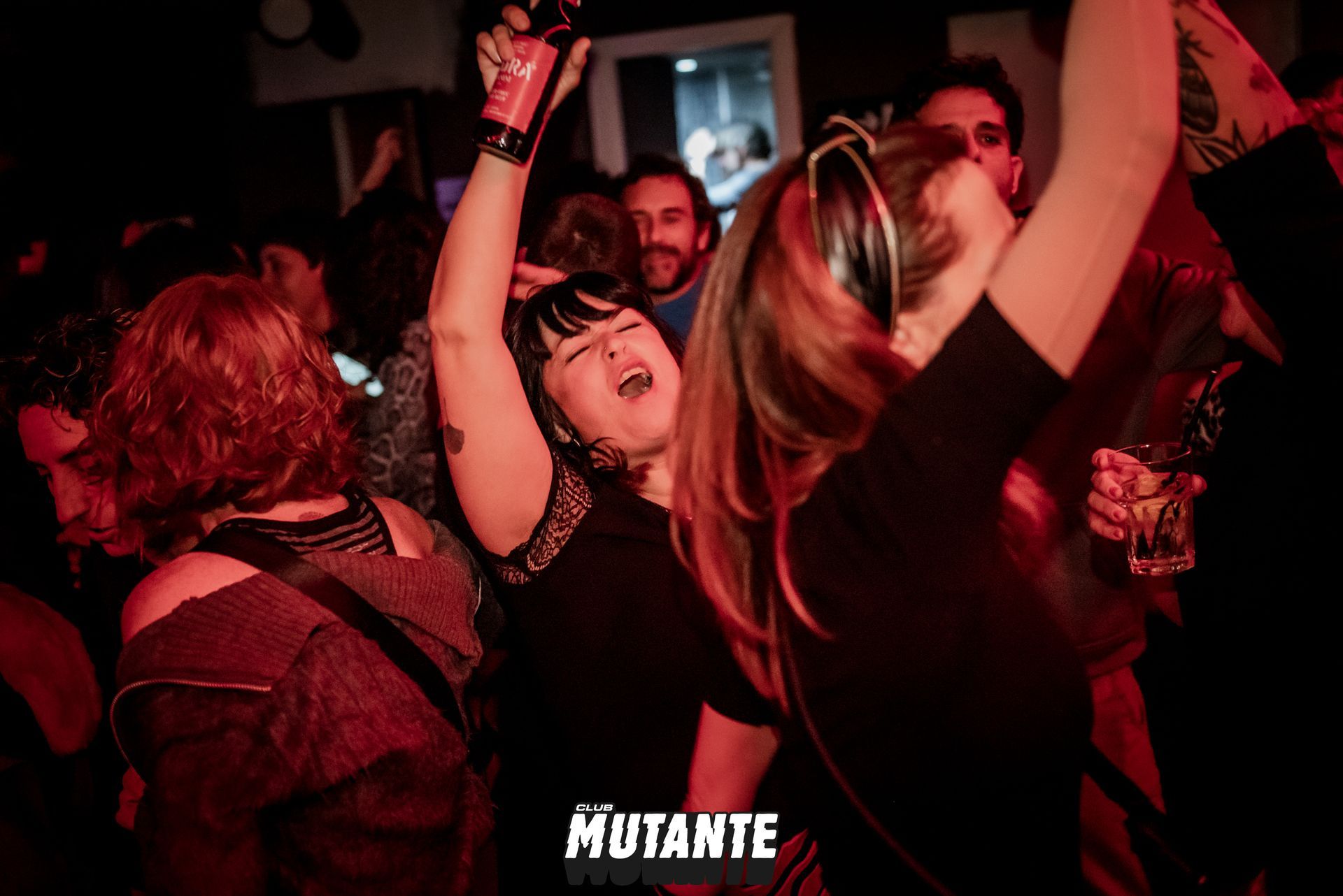 Un grupo de personas está bailando en un club con la palabra mutante en el fondo.