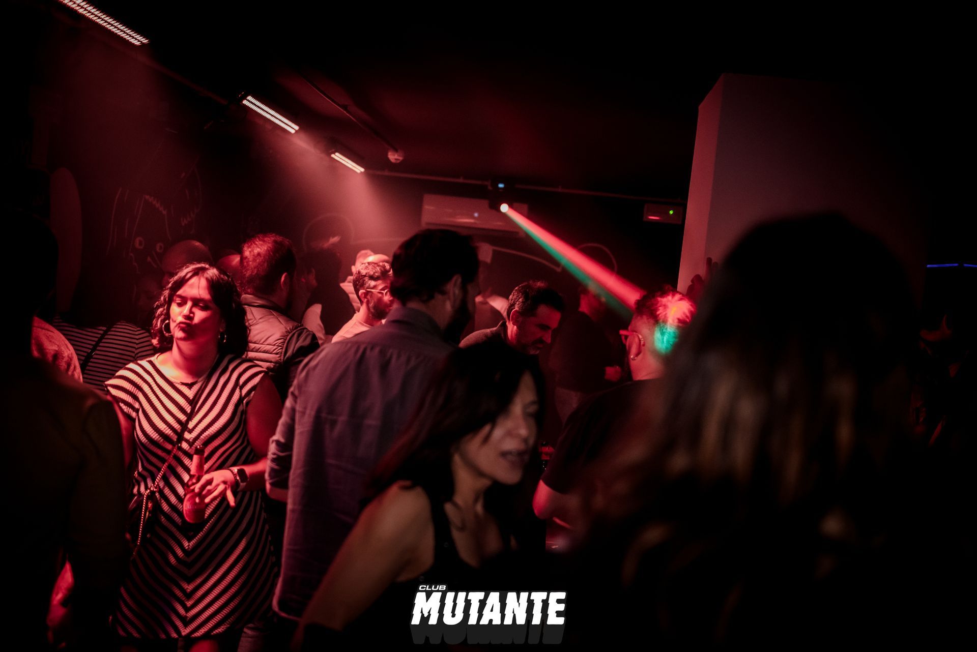 Un grupo de personas está bailando en una habitación oscura en una fiesta.
