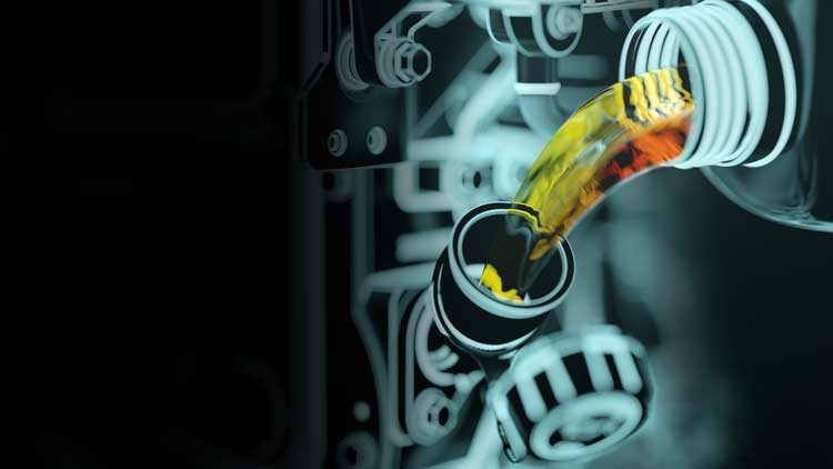 A bottle of oil is being poured into a machine.