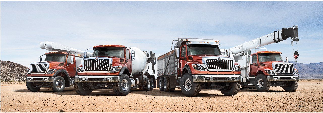 Three trucks are parked next to each other in the desert.