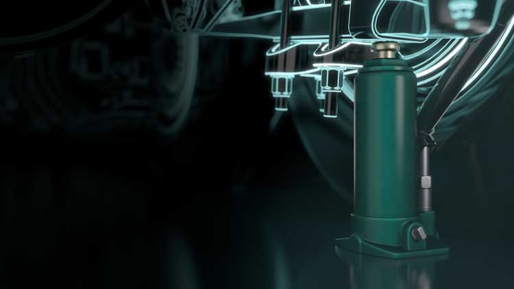 A green hydraulic jack is sitting on a black surface.