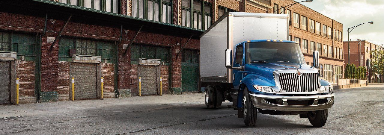 A blue and white semi truck is driving down a street in front of a brick building.