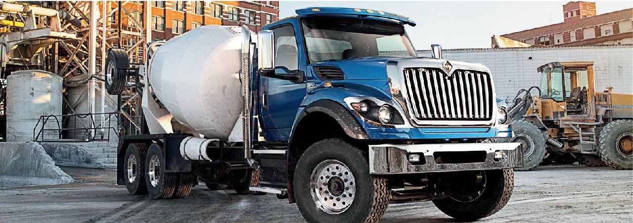 A blue and white concrete mixer truck is parked in a parking lot.