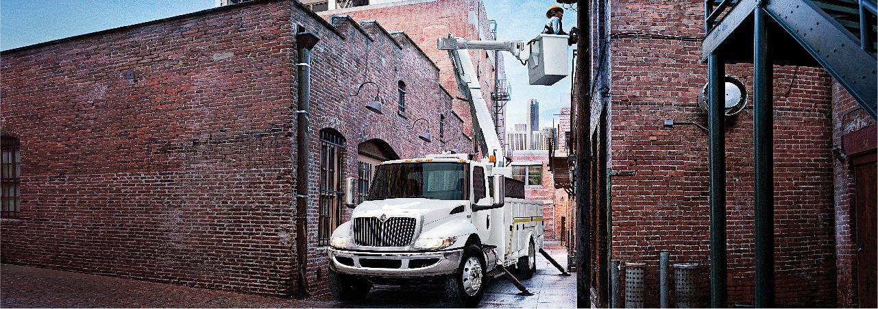A white truck is parked in a narrow alleyway next to a brick building.
