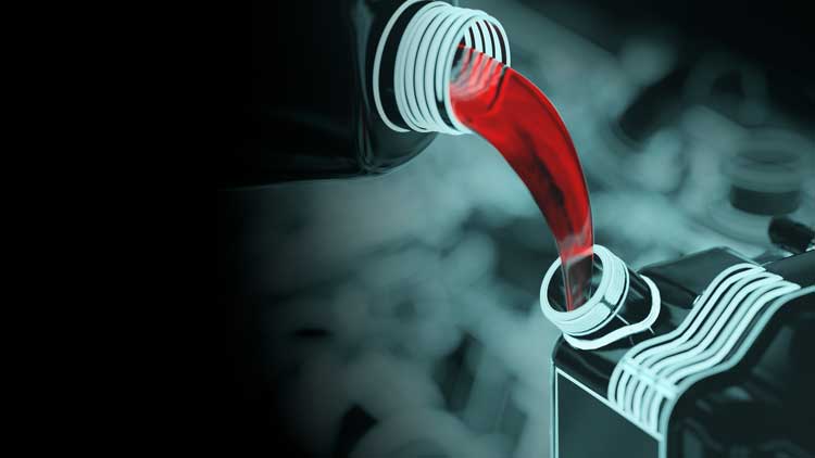 A bottle of red liquid is being poured into a container.