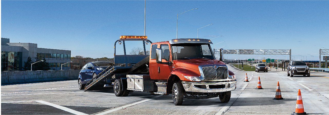 A tow truck is towing a car on a highway.