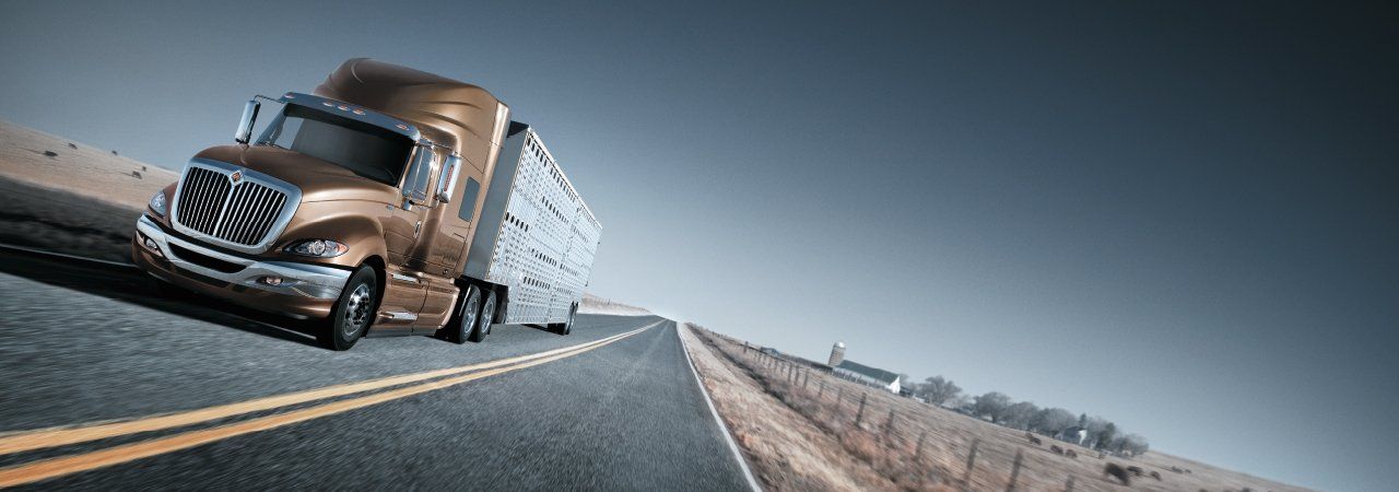 A semi truck is driving down a highway next to a field.