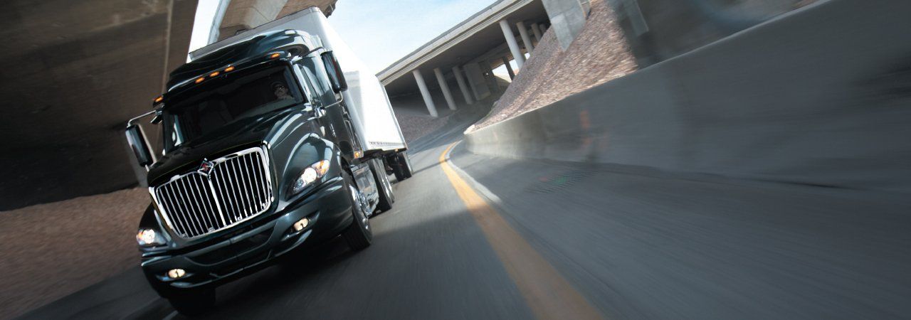 A semi truck is driving down a highway under a bridge.