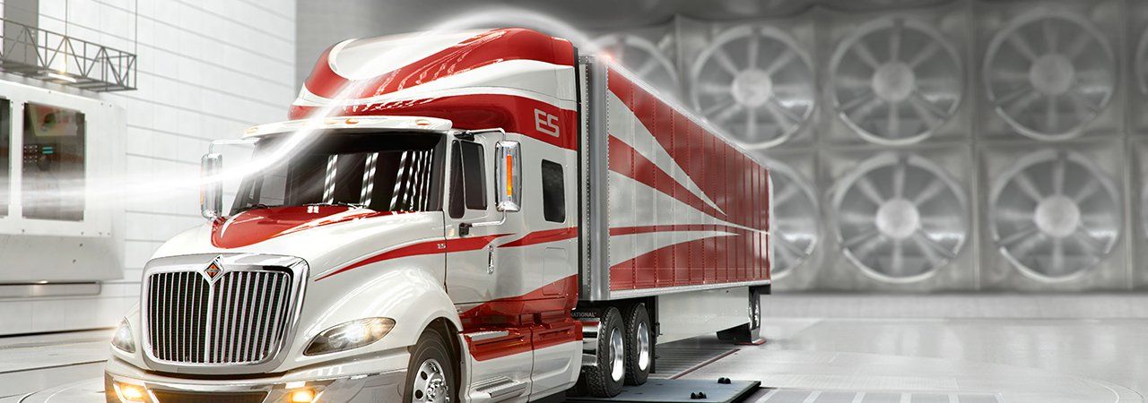 A red and white semi truck is parked in front of a wall of fans.