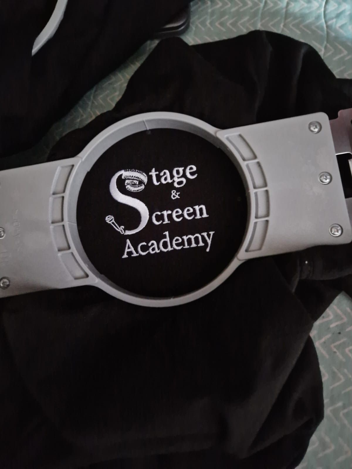 Black shirt with a gray Stage & Screen Academy logo and border.