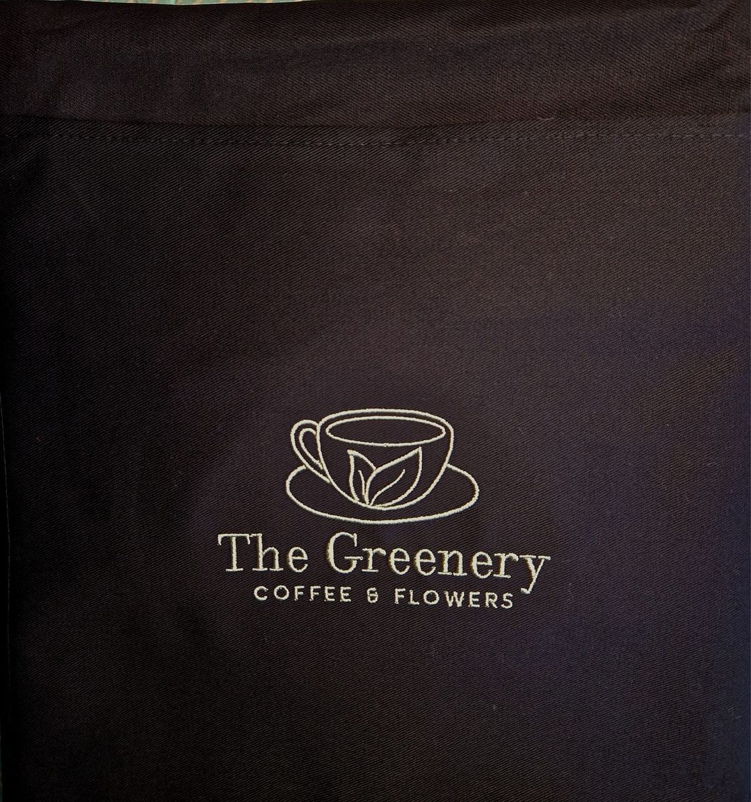 Dark blue tote bag with a white logo: a coffee cup with leaves, and the words 