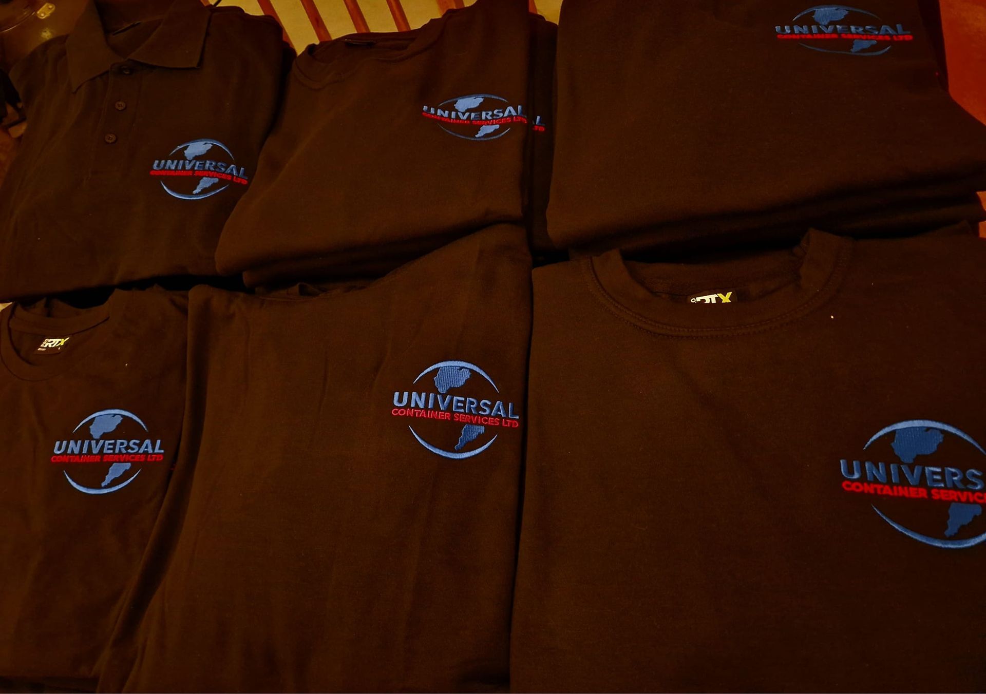 Seven black shirts with the Universal Studios logo embroidered on them.