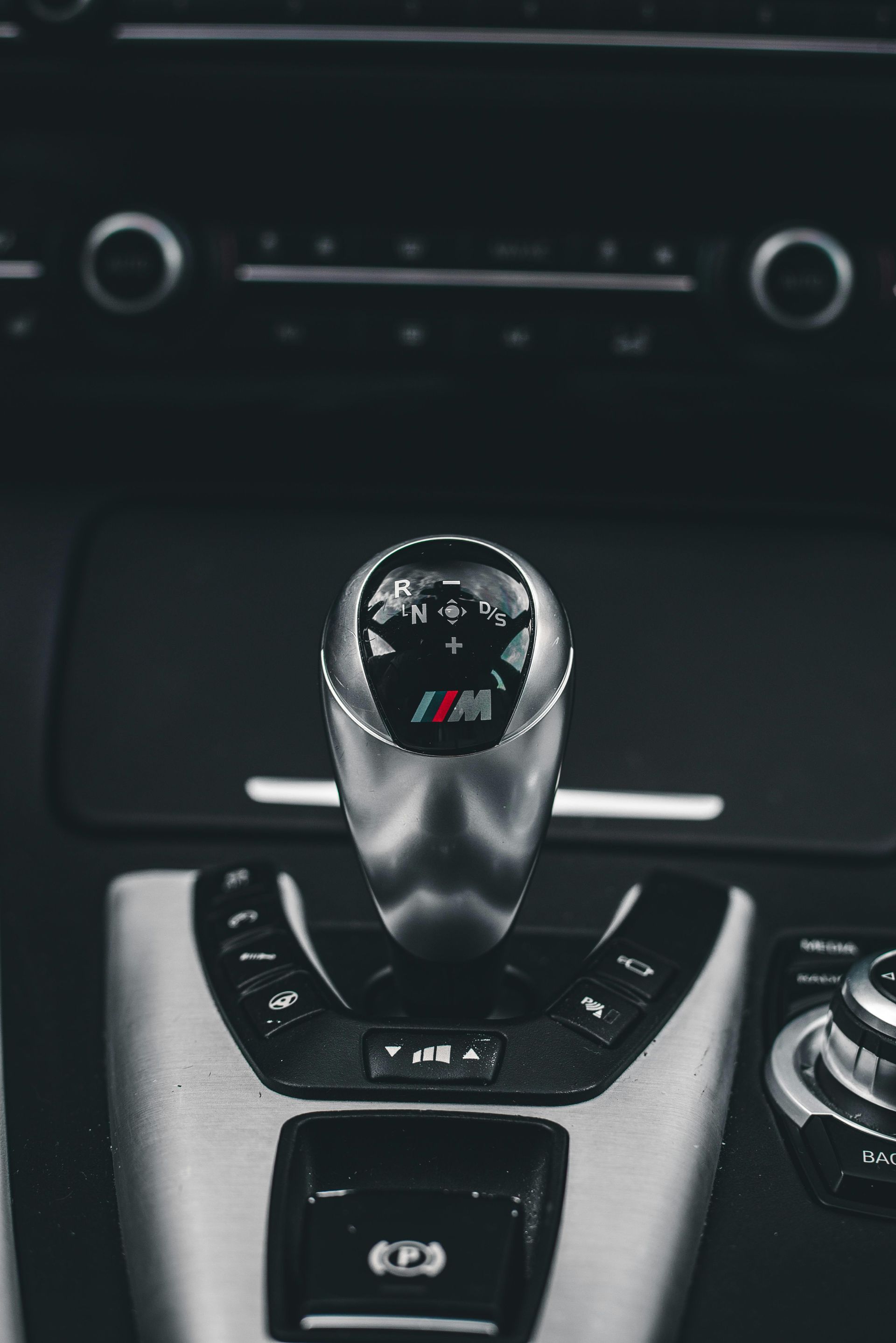 Close-up of a silver gear shift knob with the M logo in a car's interior.