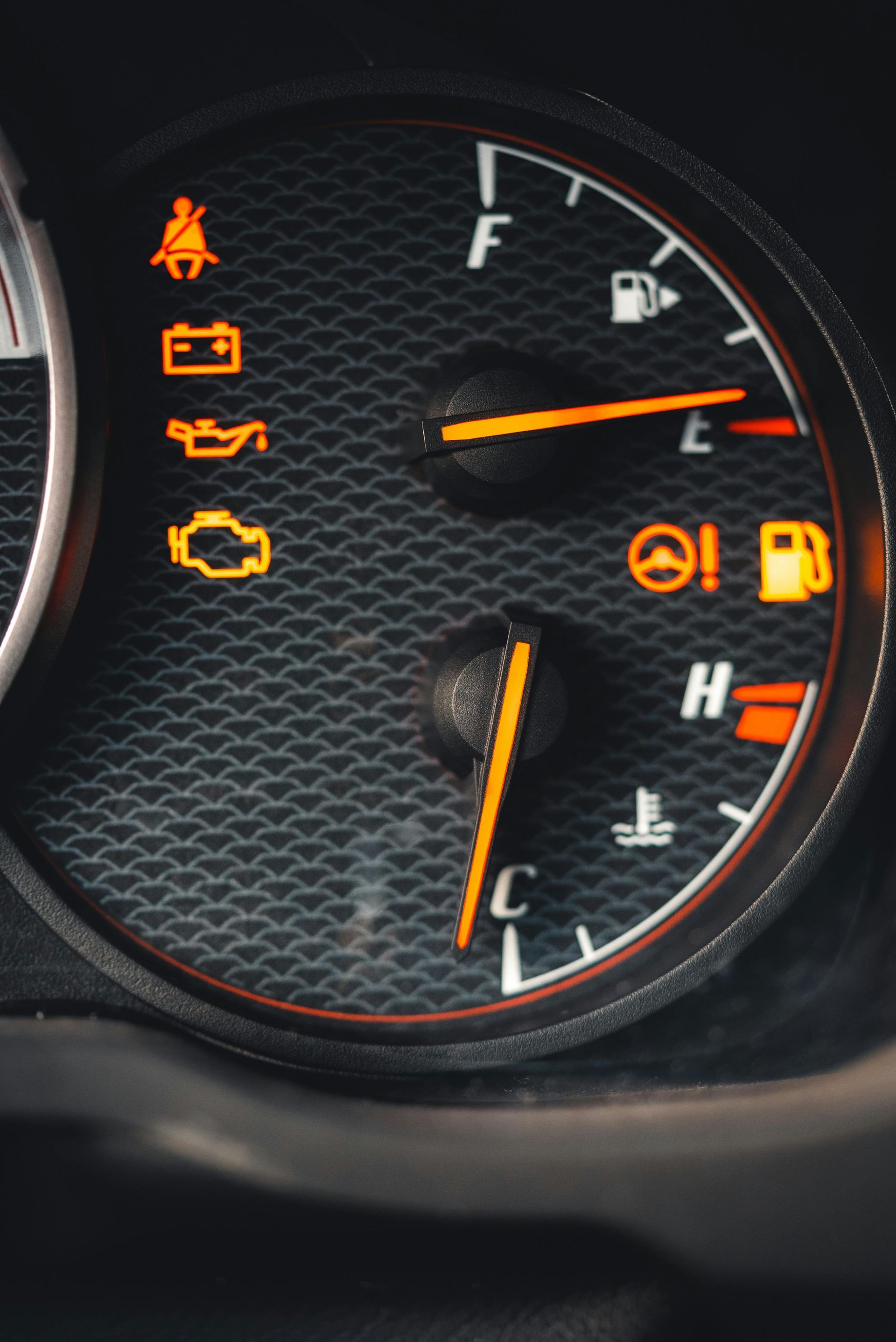 Car dashboard with illuminated warning lights, fuel gauge near empty, and temperature gauge at cold.