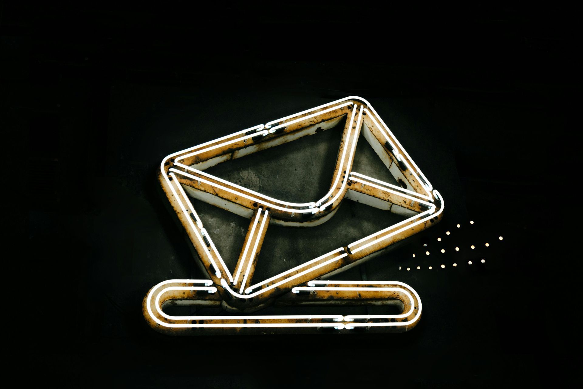 Outline of a white and gold envelope with a slot, on a black background.
