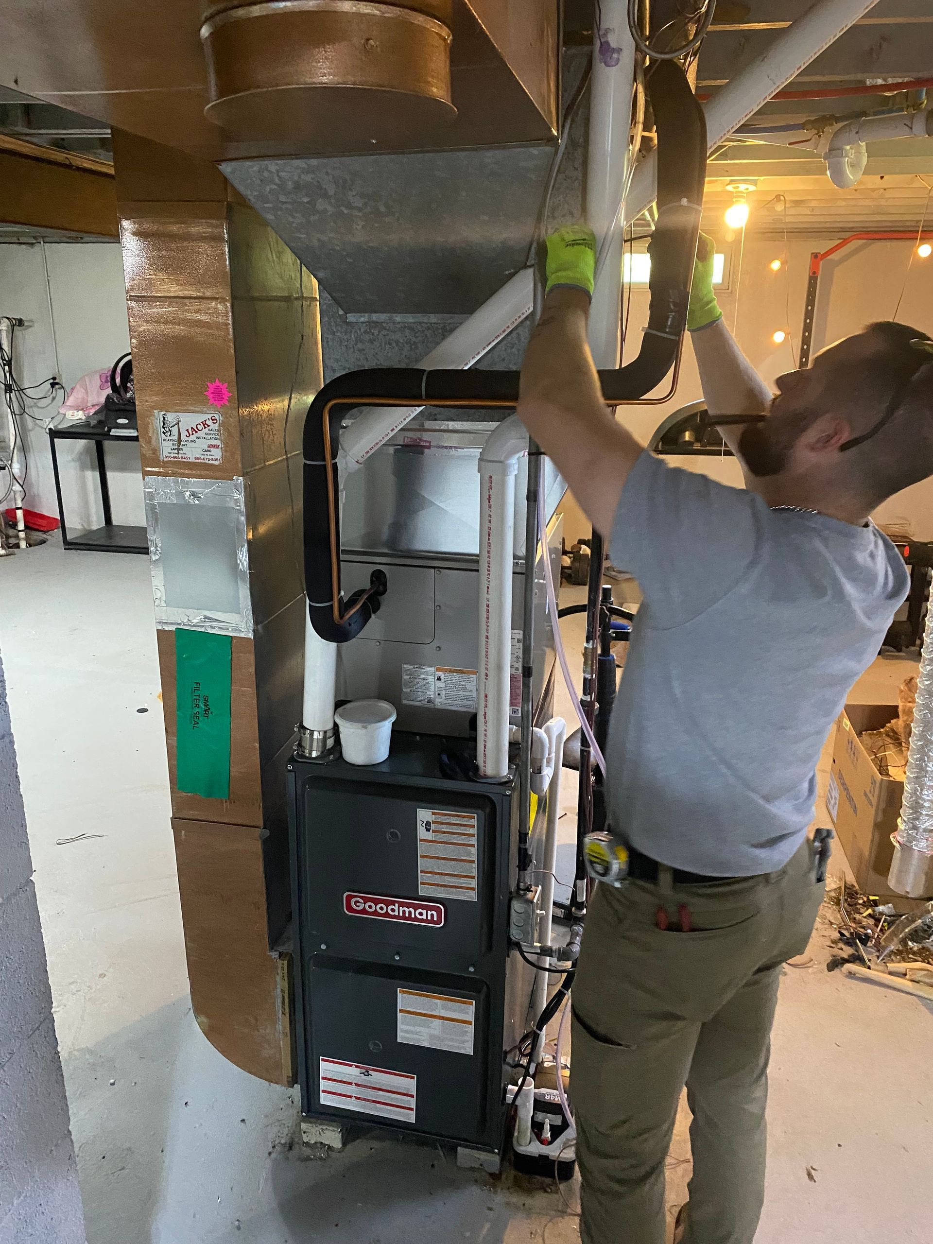 A man wearing green gloves is working on a machine.