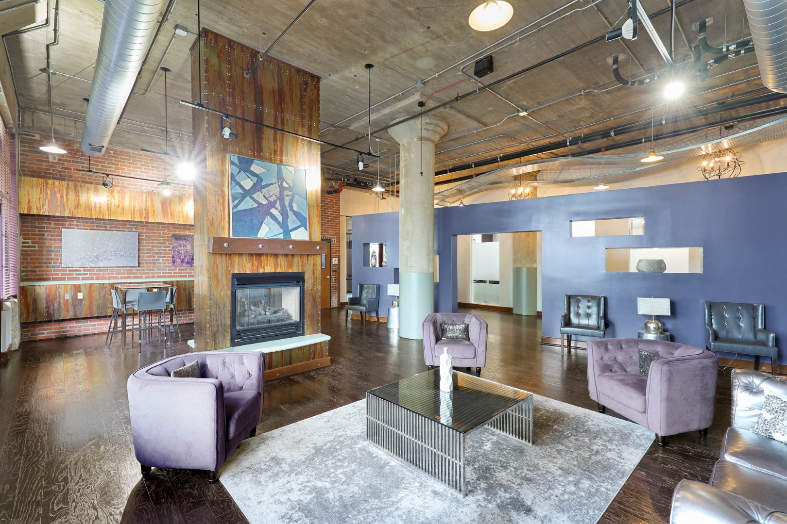 Resident lounge with purple chairs and a fireplace at The River Lofts at Tobacco Row offers apartments for rent in Richmond, VA.