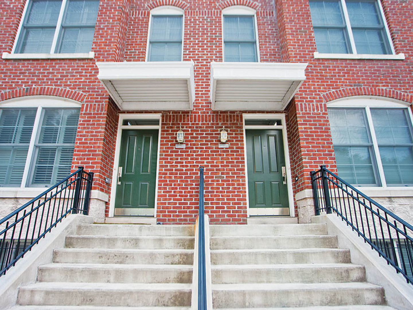 A brick building with two green doors and stairs at The River Lofts at Tobacco Row offers apartments for rent in Richmond, VA.