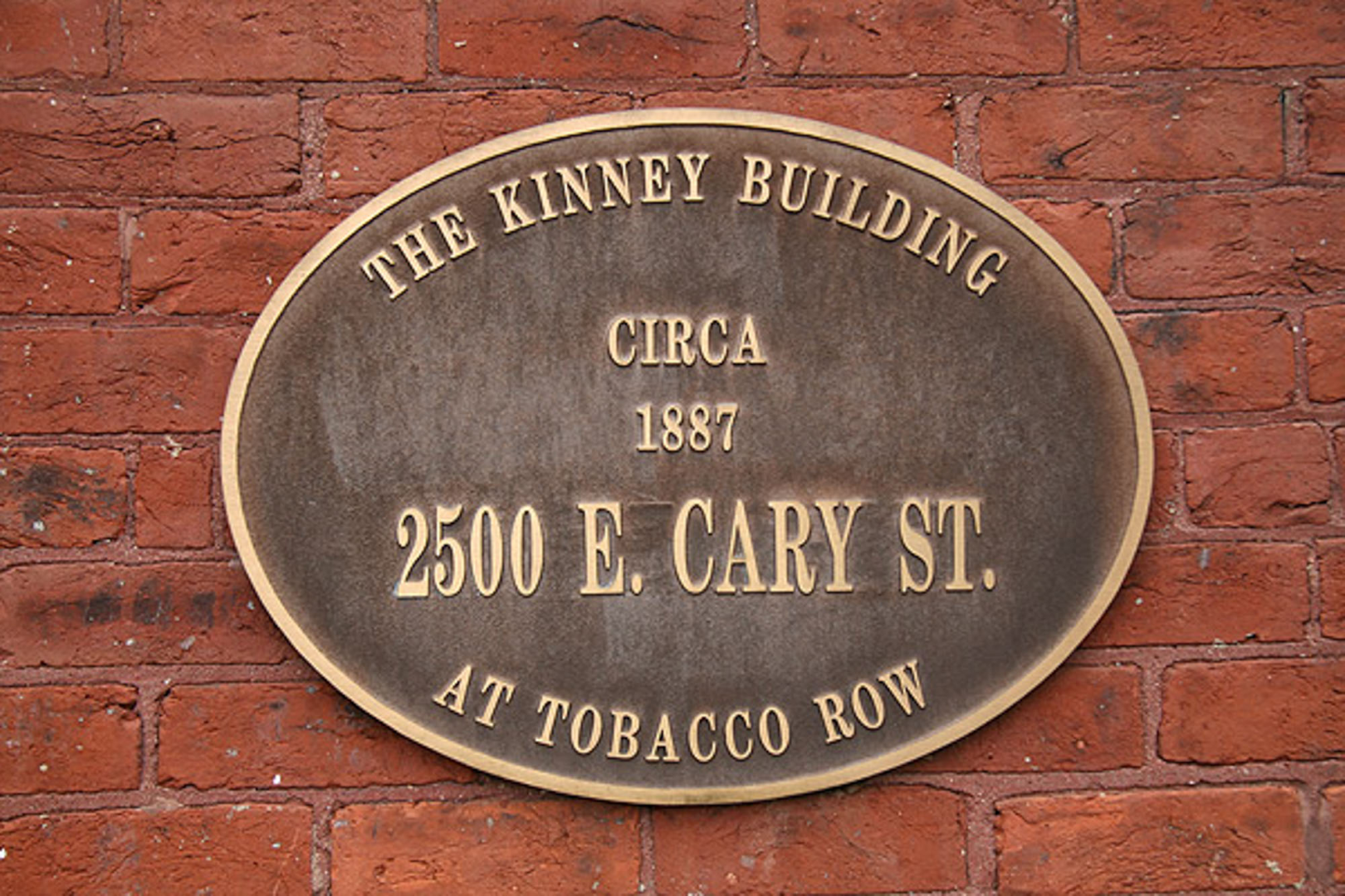 A plaque on a brick wall says the kinney building circa 1887 at The River Lofts at Tobacco Row in Richmond, VA.