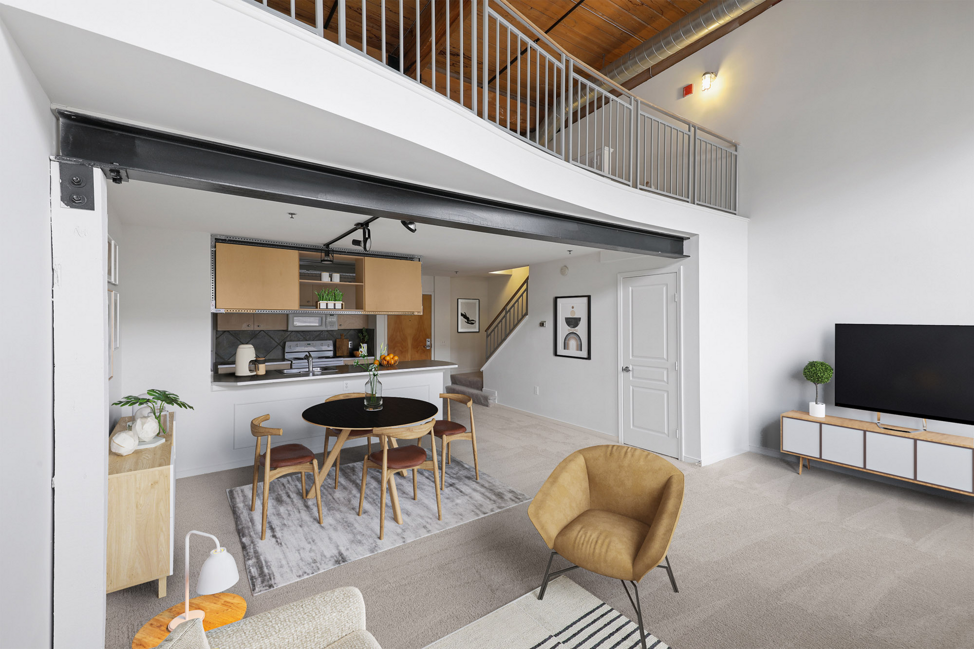 Two-floor loft-style living room with a dining table and chairs and a flat screen TV at The River Lofts at Tobacco Row offers apartments for rent in Richmond, VA.