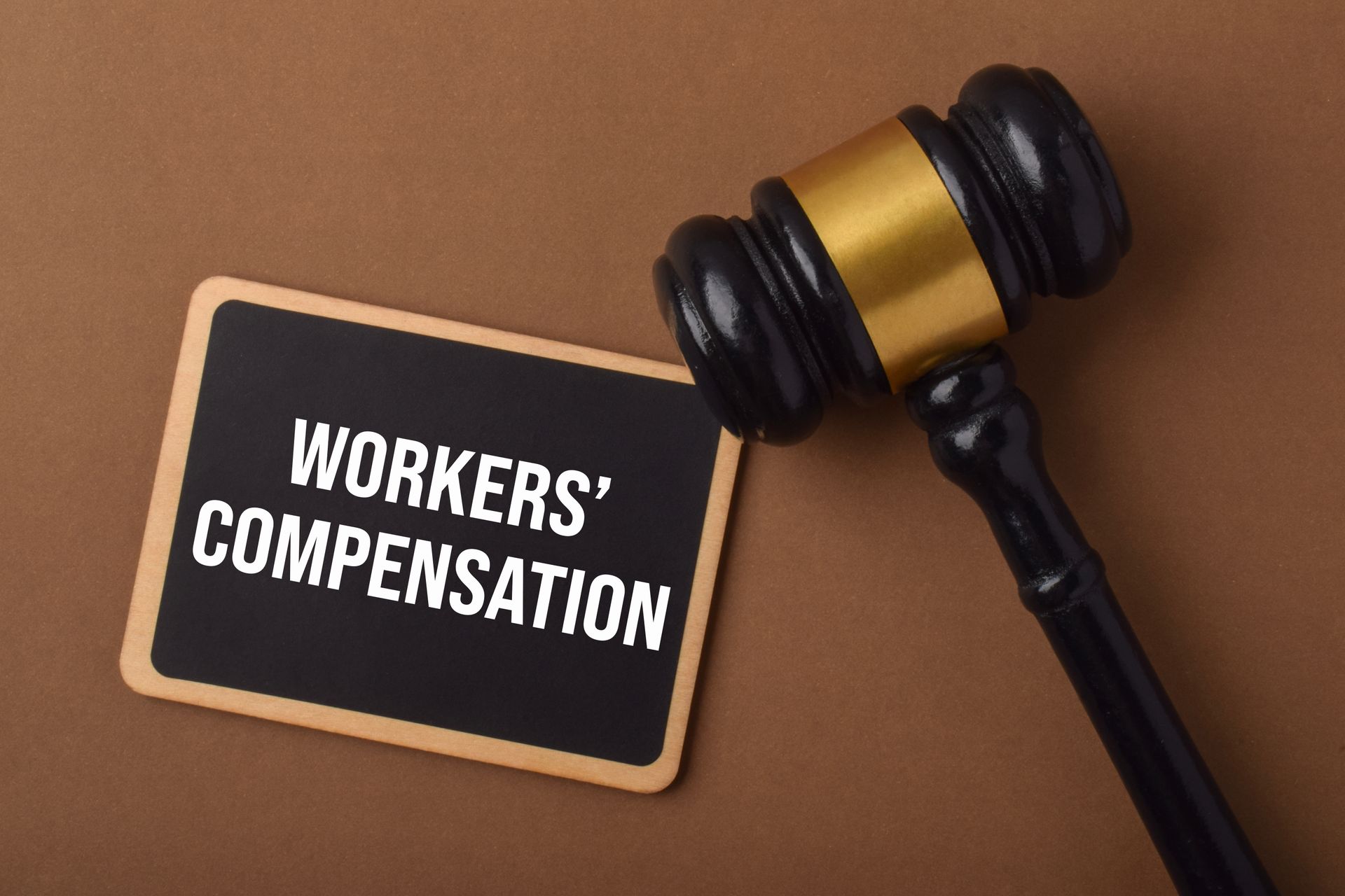 Workers' compensation sign beside a judge’s gavel on a brown background