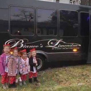 Four young children in matching patterned pants and winter coats stand in front of a black Bianco's Limousine vehicle.