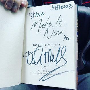 A hand holds an open book featuring a dedication by Dorinda Medley, dated 2/8/2023, with her signature below the text.