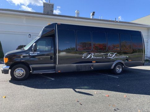 A black limousine bus parked in an outdoor lot on a sunny day, with the words "Bianco's Limousine" on the side.
