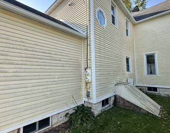 House exterior with beige vinyl siding and a tilted ramp beside the foundation