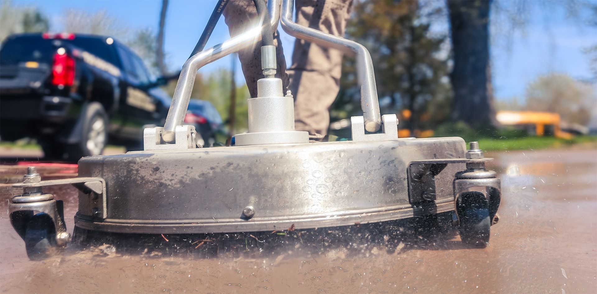 Street-cleaning machine spraying water on a wet road near parked cars