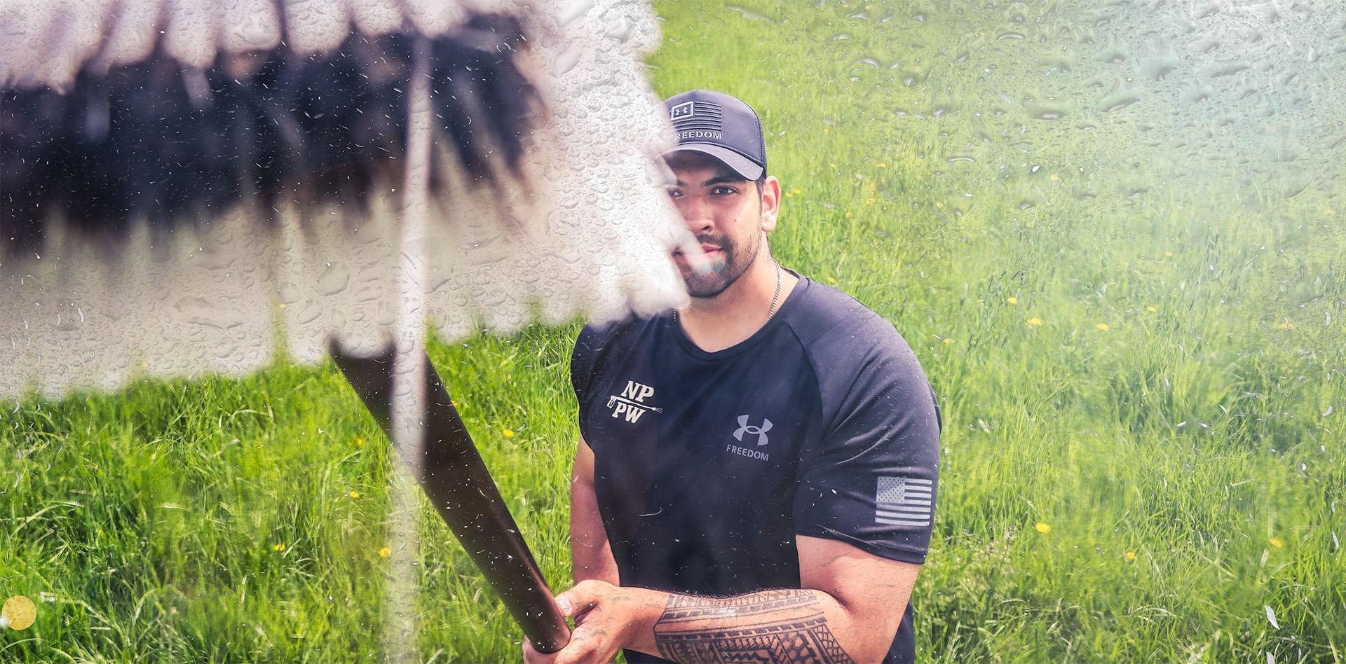 Man in black shirt holding a large net in a green outdoor field with tall grass