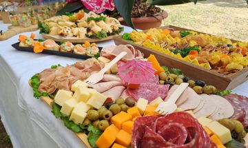 Buffet extérieur avec assortiment de fromages, charcuteries, fruits et amuse-gueules sur une nappe blanche