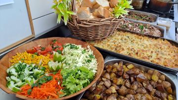 Buffet varié avec salade, légumes rôtis et un gratin cuit au four sur une table.