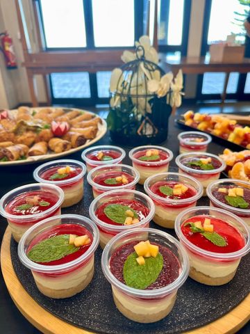 Buffet de desserts avec des verrines de pudding de chia garnies de fruits, présenté sur une table près d'une fenêtre.