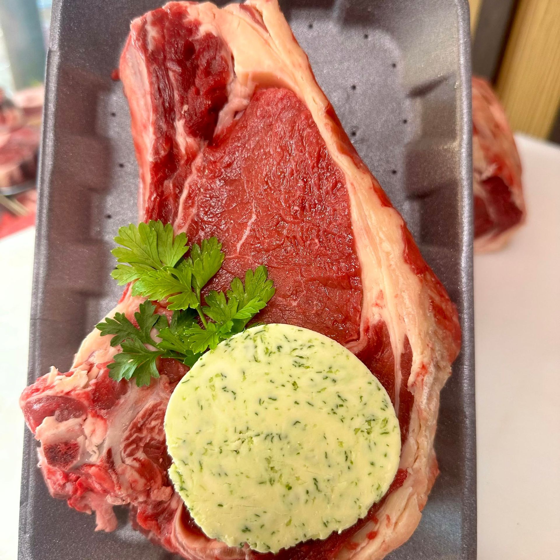 Steak cru avec beurre aux herbes sur un plateau en mousse, garni de persil