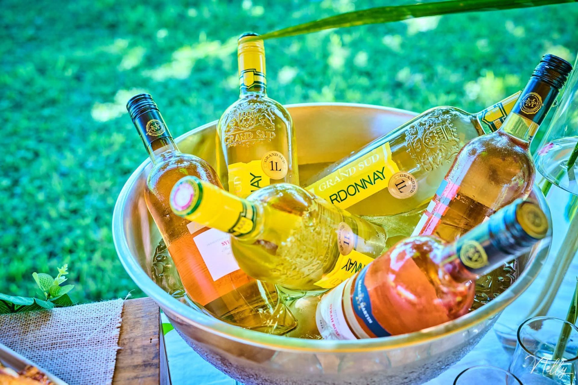 Une bouteille de rosé et d'autres bouteilles de vin dans un seau à glace, à l'extérieur sur une table ensoleillée.