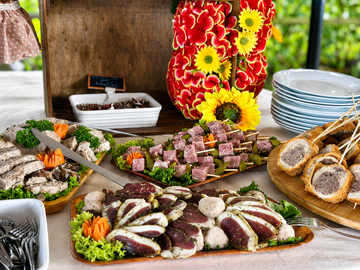 Buffet de charcuterie, fromages, pains et fleurs assortis sur une table en bois à l'extérieur